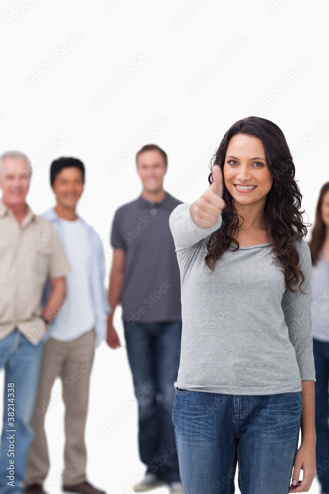 Smiling woman giving thumb up with friends behind her Smiling woman giving thumb up with friends behind her
