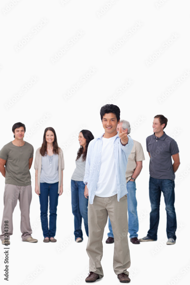 Smiling male giving thumb up with friends behind him Smiling male giving thumb up with friends behind him