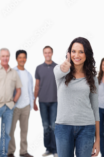 Smiling woman giving thumb up with friends behind her
