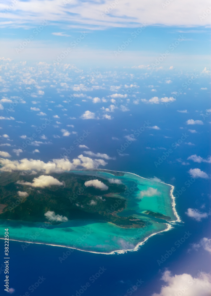 Polynesia.The atoll ring at ocean is visible through clouds.