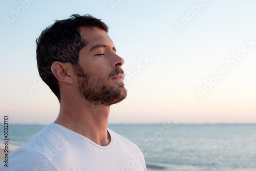 Handsome man deep breathing on the beach
