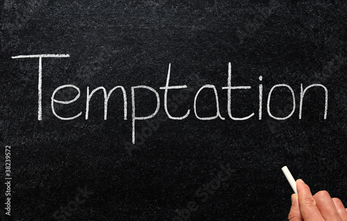 Writing temptation with white chalk on a blackboard.