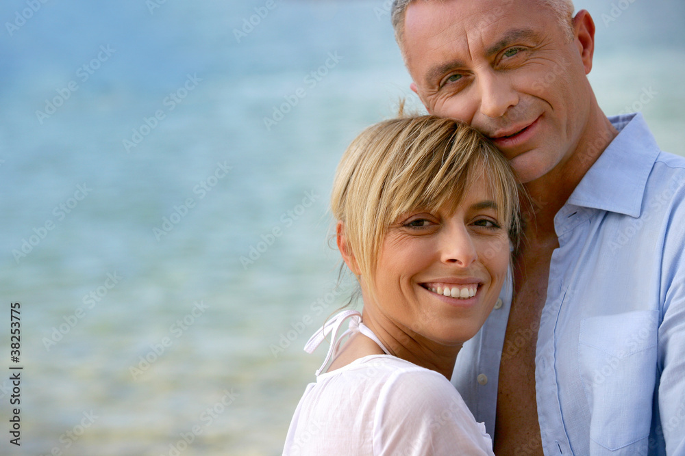 Obraz premium Couple stood hugging on romantic beach