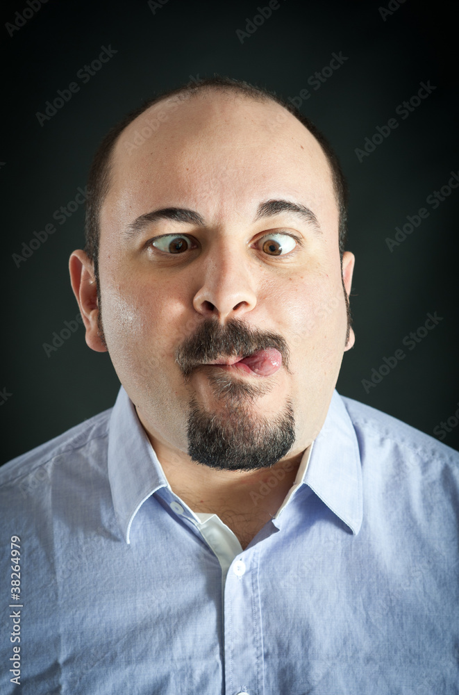 Man portrait with grimace expression on dark background. Man portrait with grimace expression on dark background.