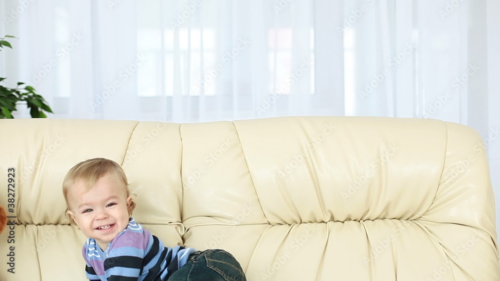 Smiling baby boy standing on the couch Smiling baby boy standing on the couch