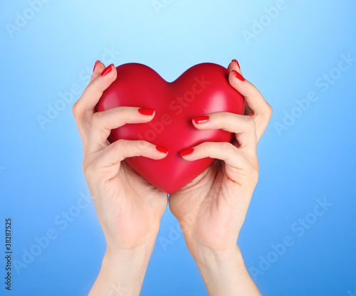 Red heart in woman s hands on blue background