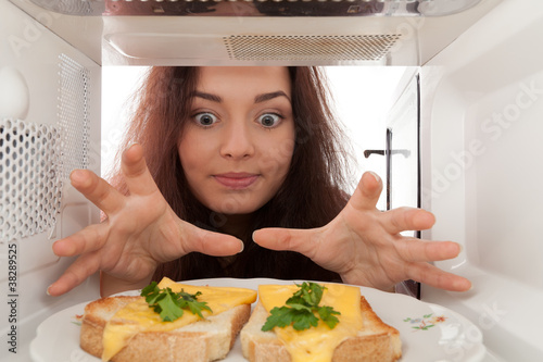 Girl looks in a microwave