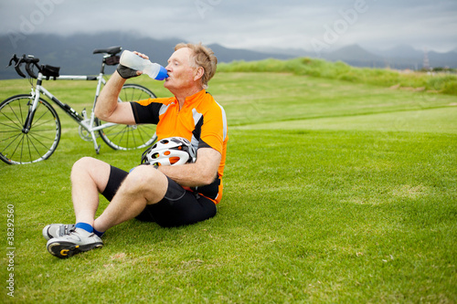 senior male cyclist taking a break and drinking water
