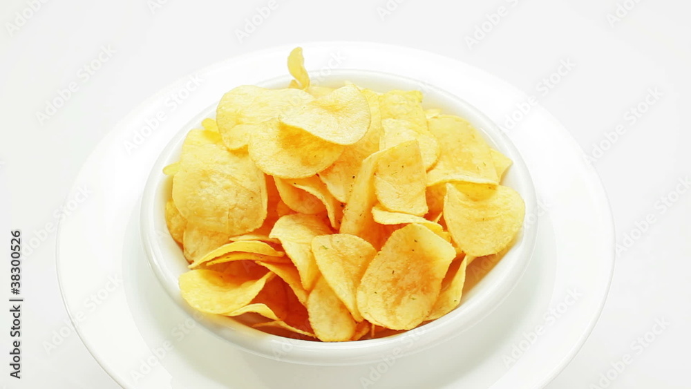 Potato chips heap rotating on a white plate, closeup view Potato chips heap rotating on a white plate, closeup view