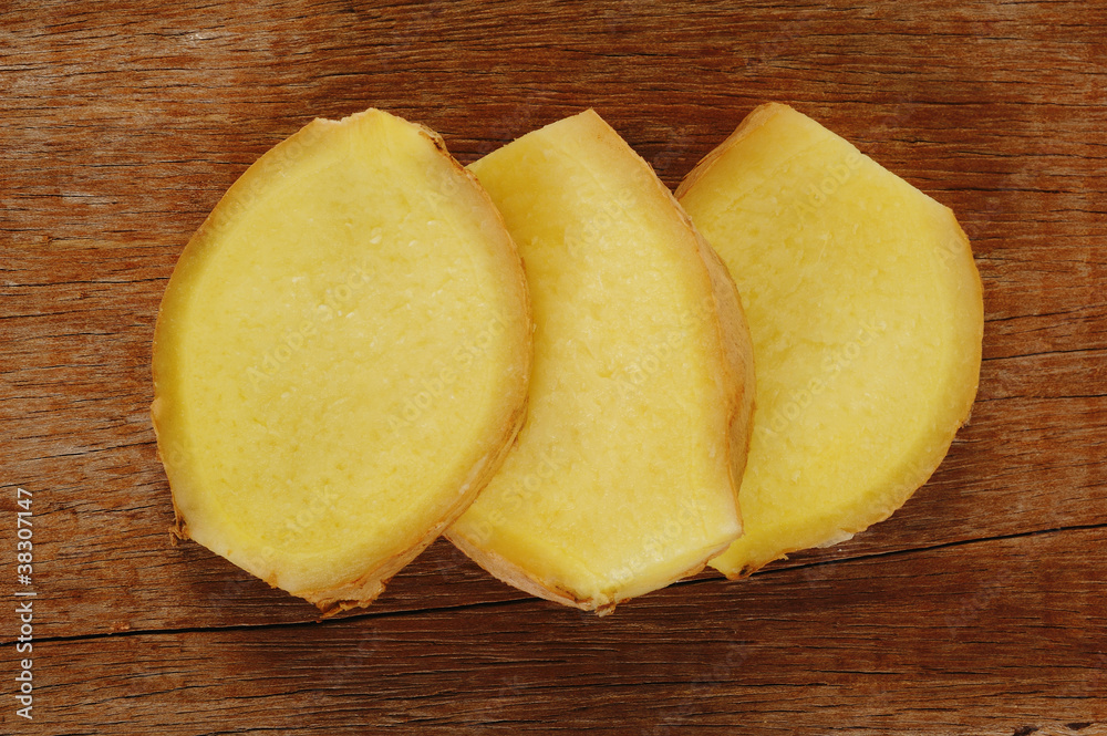 Sliced ginger root on wood background Sliced ginger root on wood background