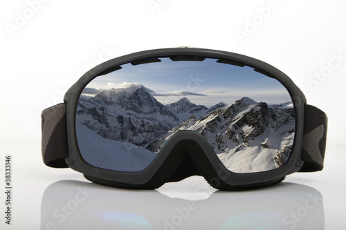 Skibrille auf weißem Untergrund mit Bergpanorama im verspiegeltem Glas