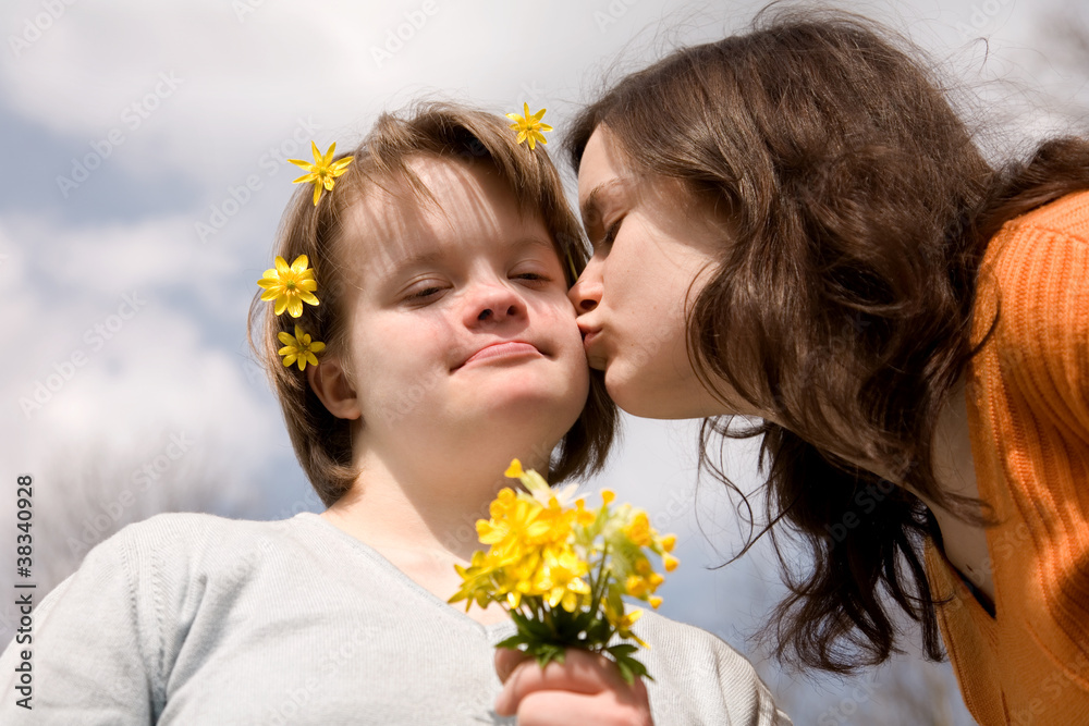Naklejka premium A girl kissing her sister with Down syndrome.