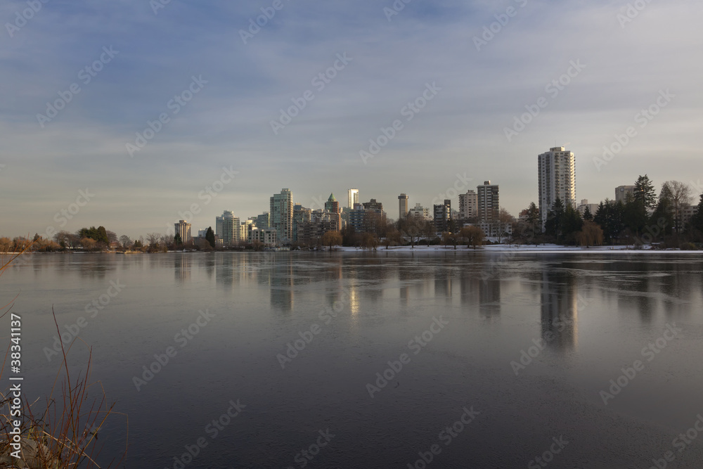 Vancouver, BC skyline reflects over frozen lost lagoon