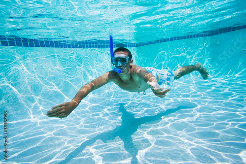 Young Man Swimming Under Water In Pool