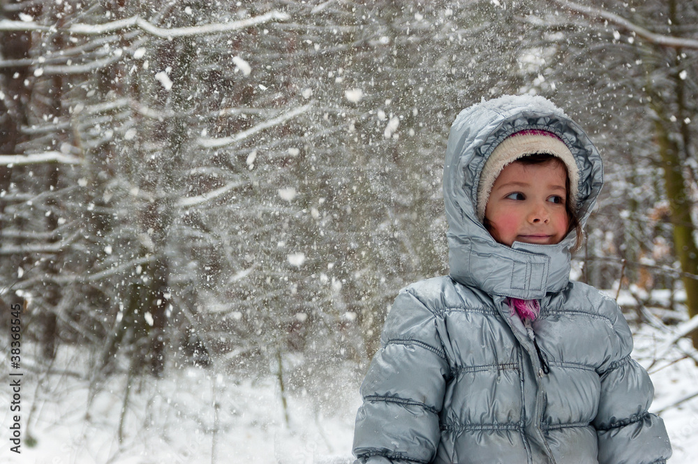 Happy child having fun in winter forest. Little girl