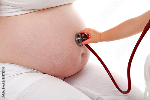 Childs hand with stethoscope on pregnant belly