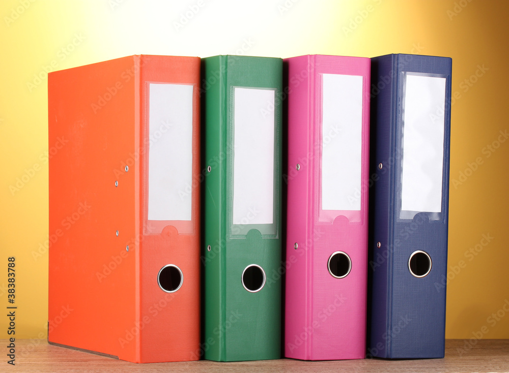 bright office folders on wooden table on yellow background. bright office folders on wooden table on yellow background.
