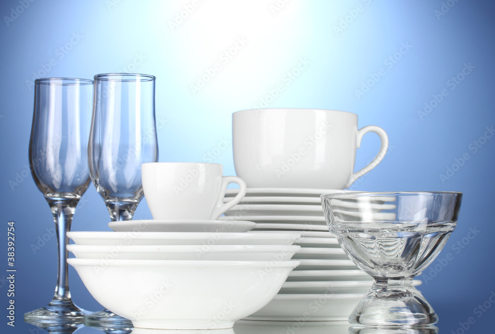 empty bowls, plates, cups and glasses on blue background empty bowls, plates, cups and glasses on blue background
