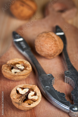 Walnuts with nutcracker on board close-up.