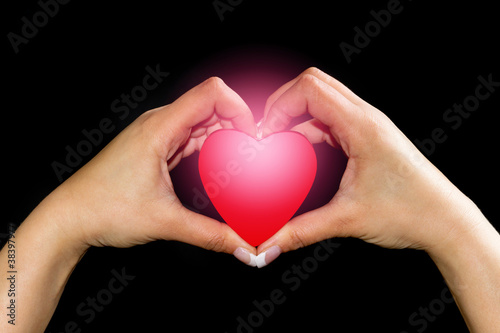 Heart in hands isolated on black