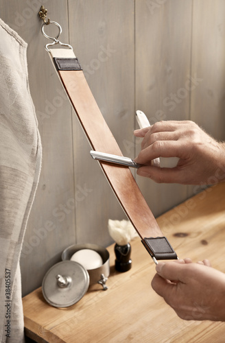 A man carefully stropping his straight razor