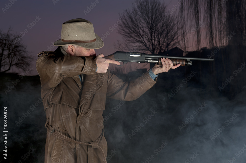 Fototapeta premium man with cowboy hat, long leather coat and riot gun