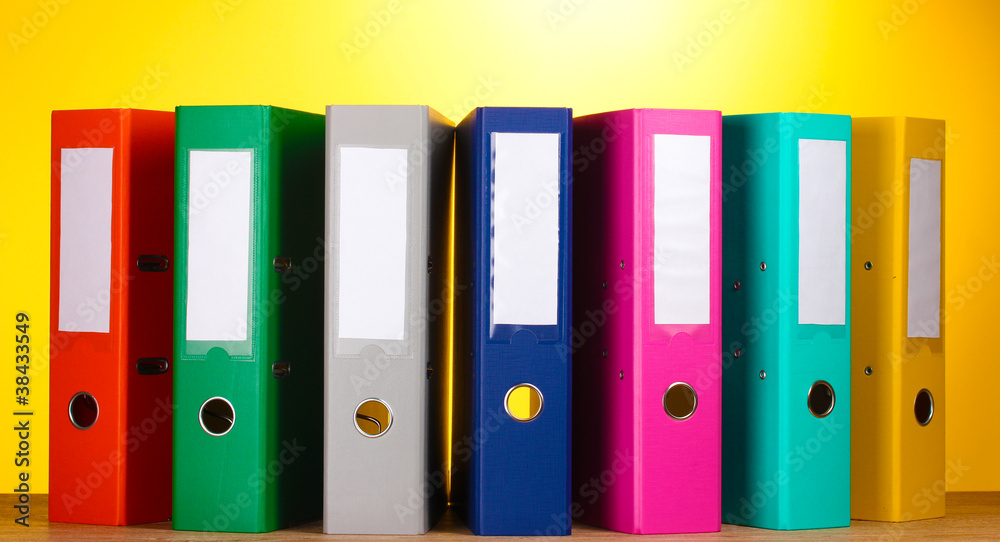 bright office folders on wooden table on yellow background bright office folders on wooden table on yellow background