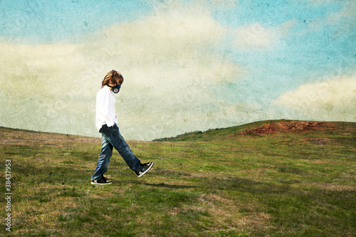A boy wearing a gas mask walking in the meadow © M-ski