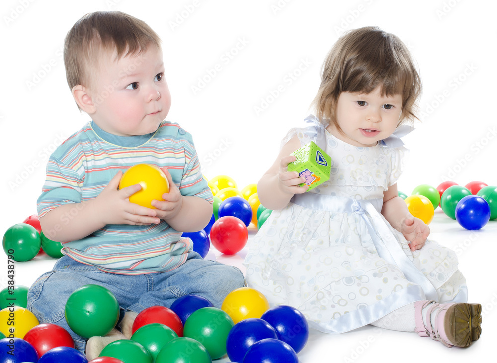The little girl and boy plays multi-coloured balls isolated The little girl and boy plays multi-coloured balls isolated