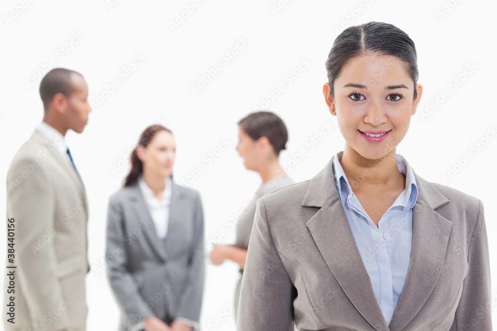 Businesswoman smiling with co-workers in the background Businesswoman smiling with co-workers in the background