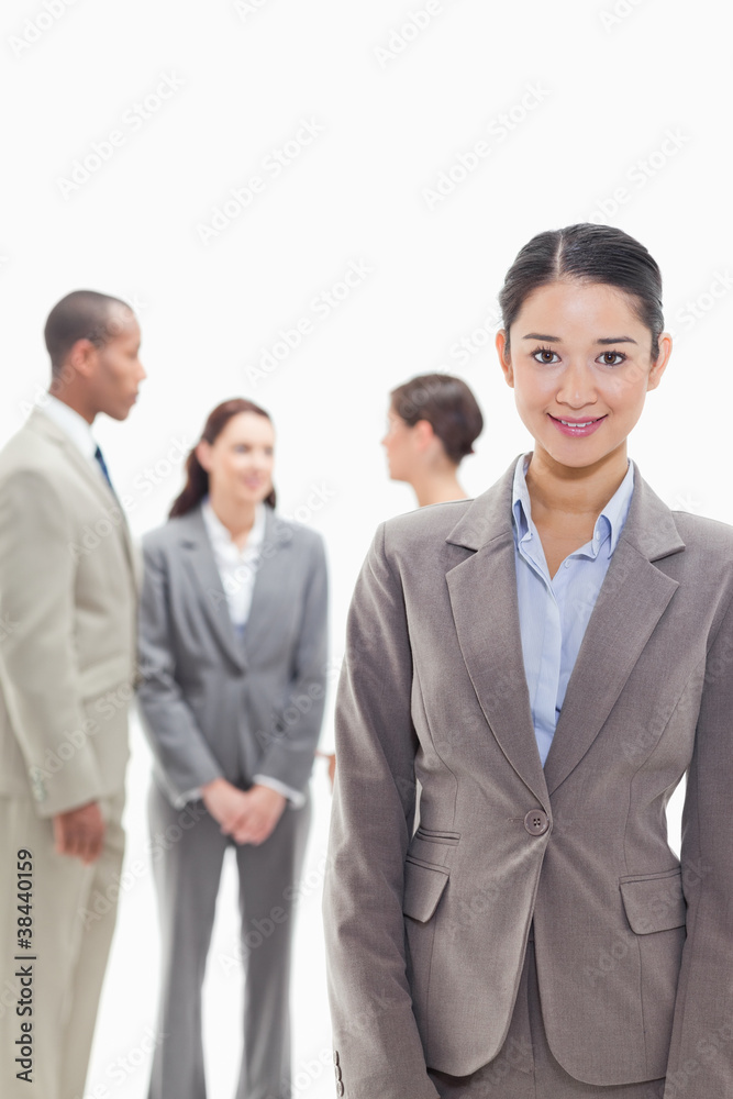 Businesswoman smiling with co-workers in the background Businesswoman smiling with co-workers in the background