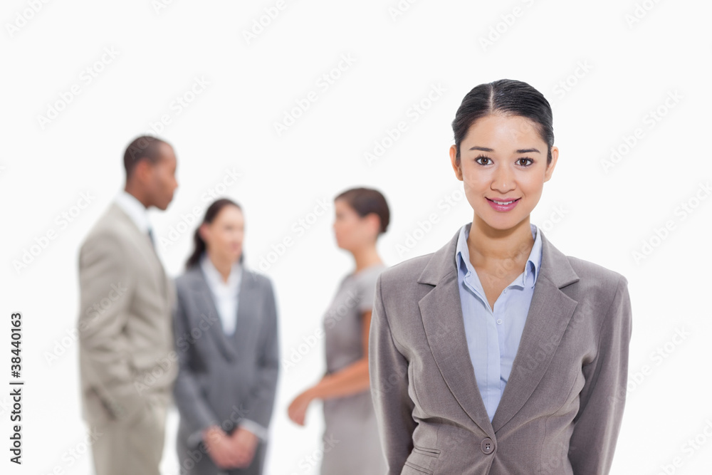 Businesswoman smiling with co-workers in the background Businesswoman smiling with co-workers in the background