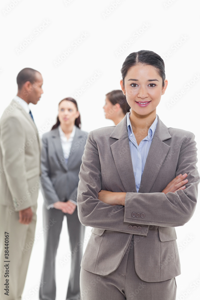 Businesswoman smiling and crossing her arms with co-workers Businesswoman smiling and crossing her arms with co-workers