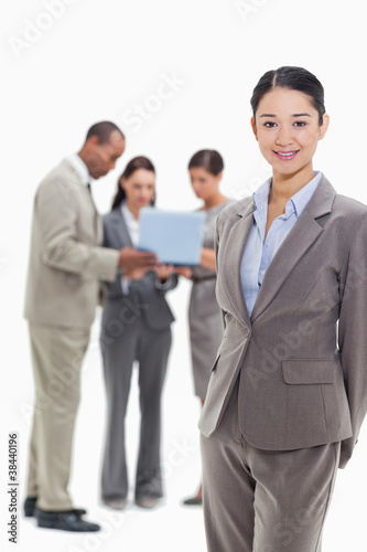 Businesswoman smiling with co-workers watching a laptop in the b