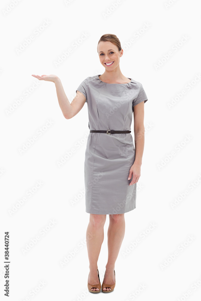 Smiling woman in a dress presenting something with her hand Smiling woman in a dress presenting something with her hand