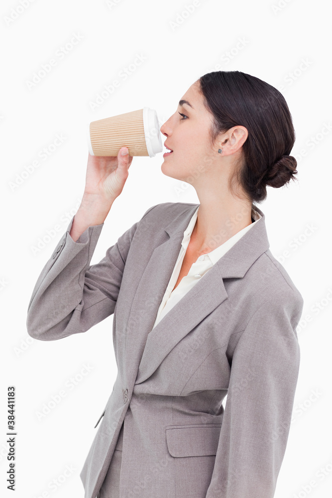 Side view of businesswoman taking a sip out of a paper cup Side view of businesswoman taking a sip out of a paper cup