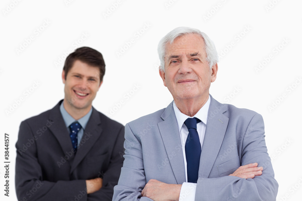 Close up of mature businessman with folded arms and colleague be Close up of mature businessman with folded arms and colleague be