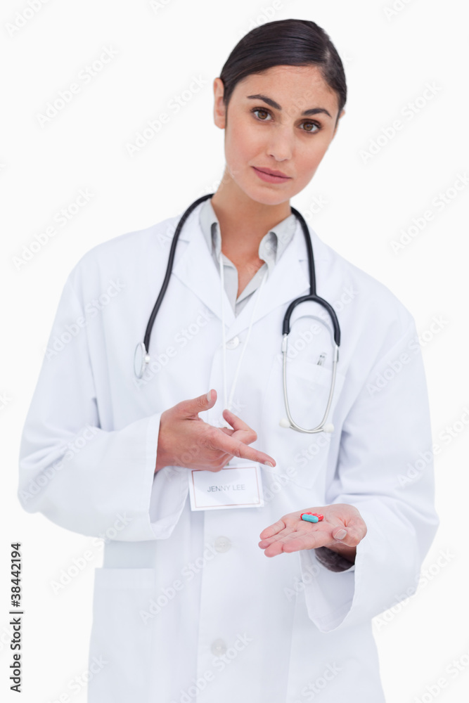Female doctor pointing at pill in her hand Female doctor pointing at pill in her hand