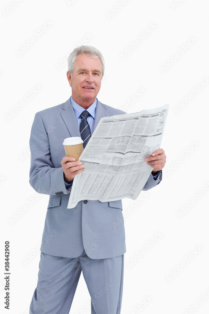 Mature tradesman holding news paper and paper cup Mature tradesman holding news paper and paper cup
