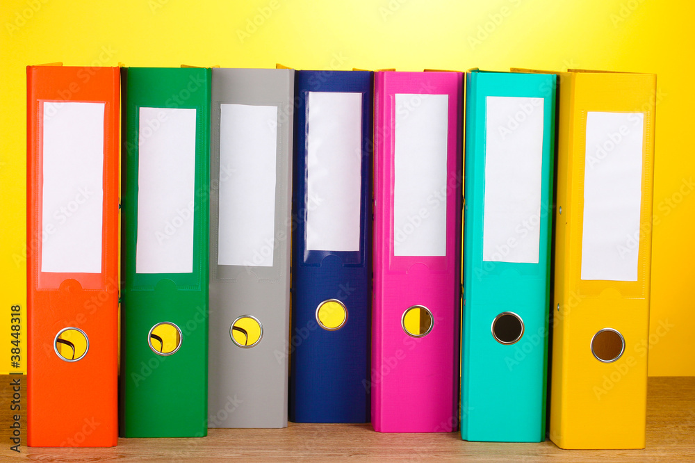 bright office folders on wooden table on yellow background bright office folders on wooden table on yellow background