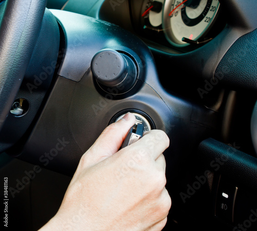 a hand turning the key to start the car