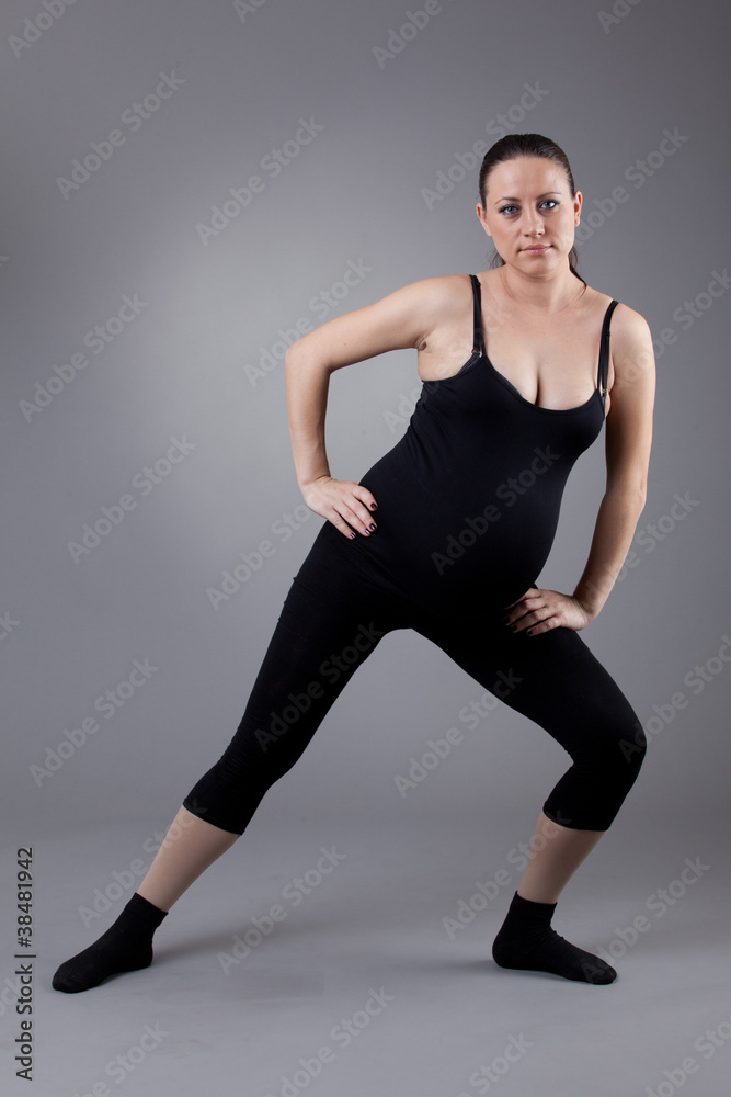 Pregnant woman doing gymnastic exercises on grey background. Pregnant woman doing gymnastic exercises on grey background.