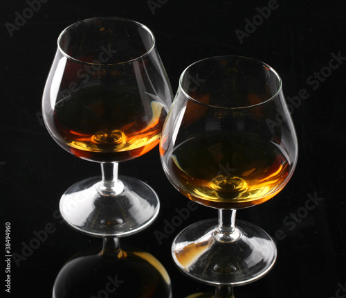 Two glasses of cognac on black background