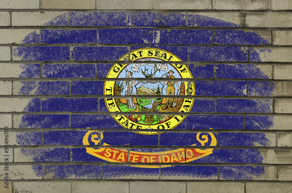 grunge flag of US state of idaho on brick wall painted with chal