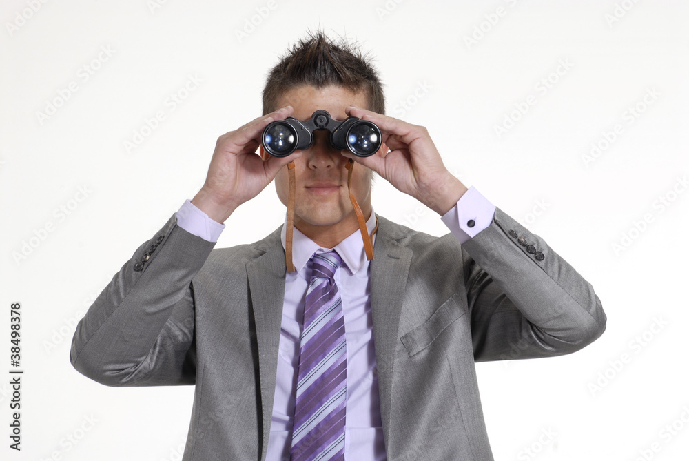 Joven ejecutivo sentado observando con binoculares. Joven ejecutivo sentado observando con binoculares.