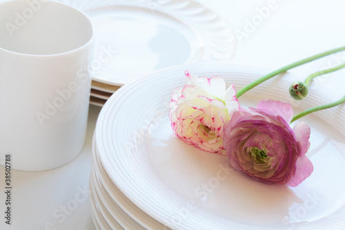 Cup and plates with flowers on white background