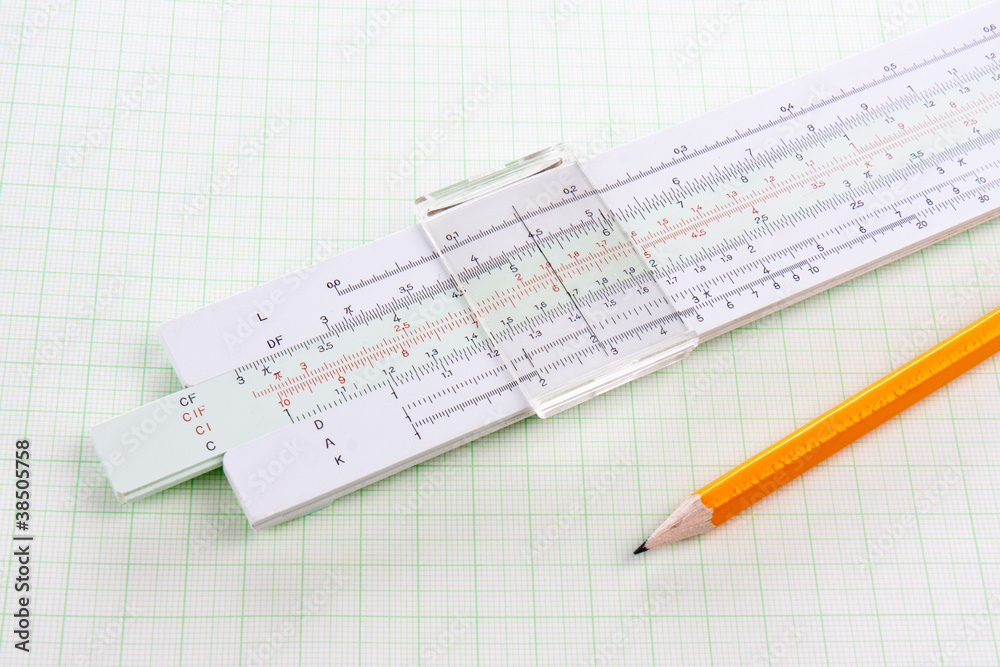 Slide rule on squared paper with wooden pencil Slide rule on squared paper with wooden pencil