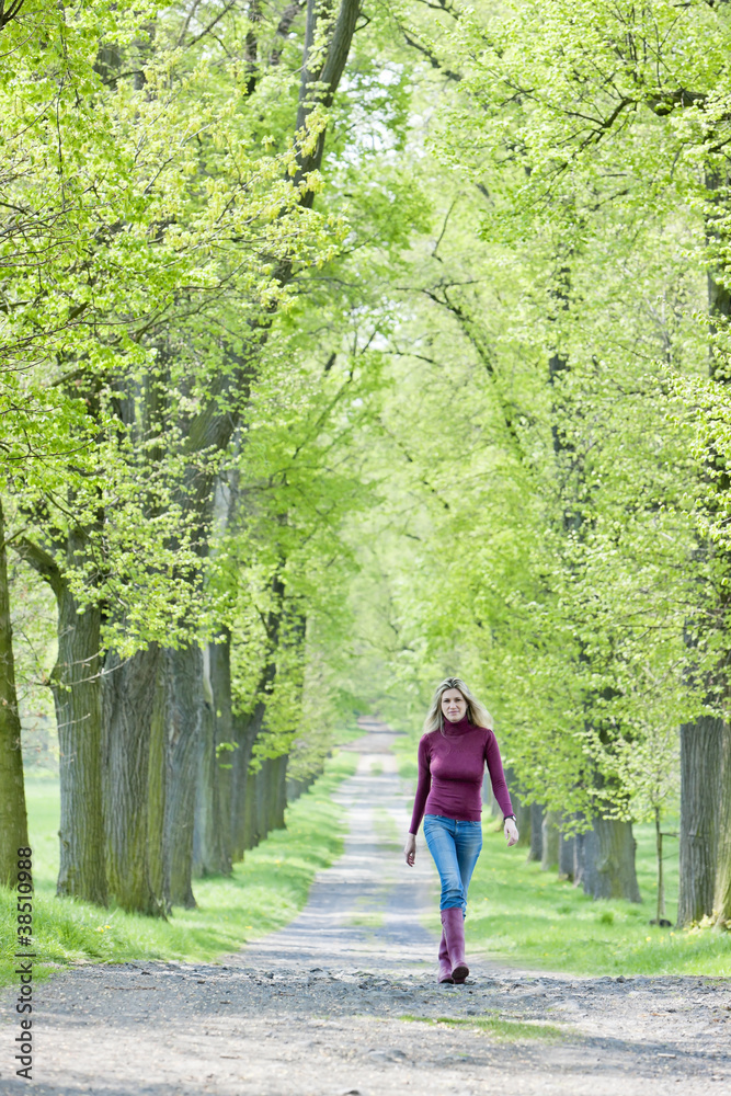 woman wearing rubber boots in spring alley woman wearing rubber boots in spring alley