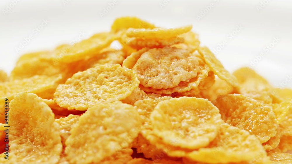 Corn flakes heap rotating on a white plate closeup view Corn flakes heap rotating on a white plate closeup view