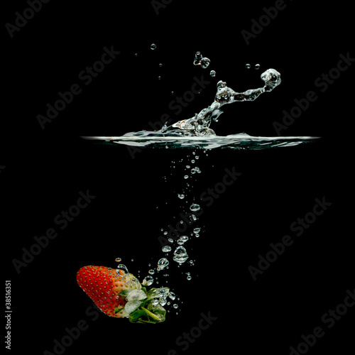 strawberry splashing in water over black background